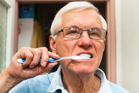 older man brushing teeth